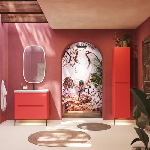 Badezimmer-Inspiration mit roten Wänden, sanft geformtem roten Waschtischunterschrank und Hochschrank, elegantem weißen Waschbecken und schönem ovalem Spiegel mit Beleuchtung, die zusammen mit der natürlichen Umgebung ein Vintage-Flair schaffen