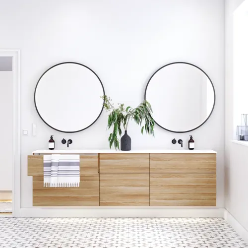 Nordisches Badezimmer aus Holz mit schönen runden Spiegeln mit schwarzen Kanten und viel Stauraum in den Badezimmermöbeln