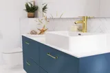 Badezimmer Inspiration mit Badezimmerschränken in moderner blauer Farbe, eleganter Aufsatzwaschbecken und großem quadratischem Spiegel mit Licht, weiße Fischgrätfliesen sorgen für einen stilvollen und klassischen Look