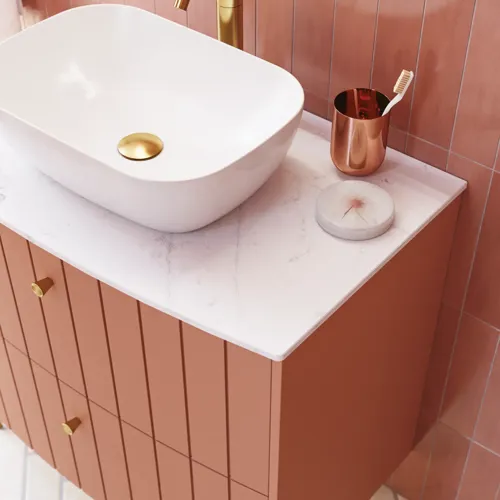 Großes Vintage-Badezimmer mit terrakottafarbenem Waschtisch, Aufsatzwaschbecken, ovalem Spiegel mit Messingrand, rosa und grauen Fliesen, romantisch und feminin