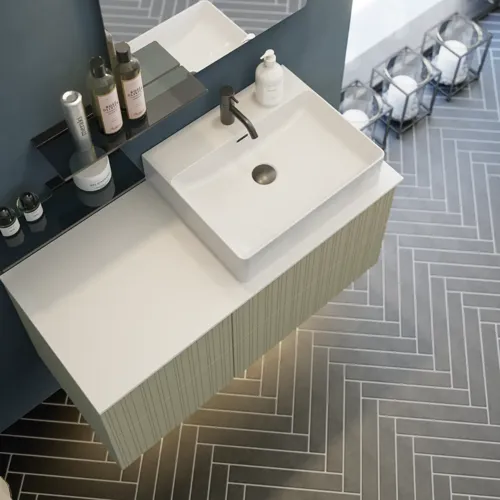 Badezimmer mit schräger Decke, beige Möbel mit Rillen, elegante Arbeitsplatte und quadratisches Waschbecken, schöner Spiegel mit Regalen, blaue Wände, große Fenster und schwarzer Fischgrätboden für ein helles, urbanes Aussehen.