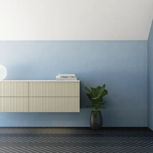 Badezimmer mit schräger Decke, beige Möbel mit Rillen, elegante Arbeitsplatte und quadratisches Waschbecken, schöner Spiegel mit Regalen, blaue Wände, große Fenster und schwarzer Fischgrätboden für ein helles, urbanes Aussehen.