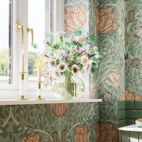 Badezimmerinspiration mit grünen Möbeln in Sonderfarbe mit Seiten aus naturbelassener Eiche, eleganten Rillen, stilvoller Arbeitsplatte mit ovalem Aufsatzwaschbecken, schönem ovalem Spiegel und Blumenmuster-Tapete für ein anmutiges, Retro-Aussehen.