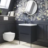Badezimmer-Inspiration mit dunkelblauen Wandpaneelen, romantischer Blumen-Tapete, dunkelblauem Waschtischunterschrank mit weichen Formen und einem schönen runden Spiegel mit Beleuchtung, das ein Vintage-Flair verleiht