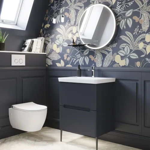 Badezimmer-Inspiration mit dunkelblauen Wandpaneelen, romantischer Blumen-Tapete, dunkelblauem Waschtischunterschrank mit weichen Formen und einem schönen runden Spiegel mit Beleuchtung, das ein Vintage-Flair verleiht
