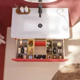 Badezimmer-Inspiration mit roten Wänden, sanft geformtem roten Waschtischunterschrank und Hochschrank, elegantem weißen Waschbecken und schönem ovalem Spiegel mit Beleuchtung, die zusammen mit der natürlichen Umgebung ein Vintage-Flair schaffen