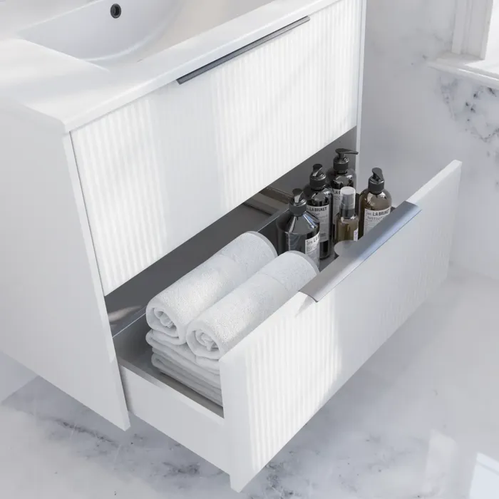 Badezimmer-Inspiration mit weißem Waschtischunterschrank mit eleganten Rillen und schönem Waschbecken, weißen Marmorwänden und -böden für einen hellen und modernen Look.