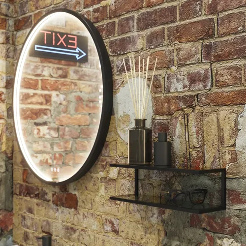 Rohes und modernes Badezimmer im urbanen Stil. Schöne Waschtischunterschränke und runde Spiegel mit schwarzer Zierleiste