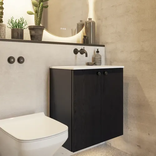 Badezimmerinspiration mit Waschtischunterschrank aus schwarzer Eiche sowie elegantem rundem Spiegel und Waschbecken, stilvollen Accessoires sowie Kaktuspflanzen und Wänden aus rohen Materialien verleihen einen rauen, industriellen und urbanen Look.