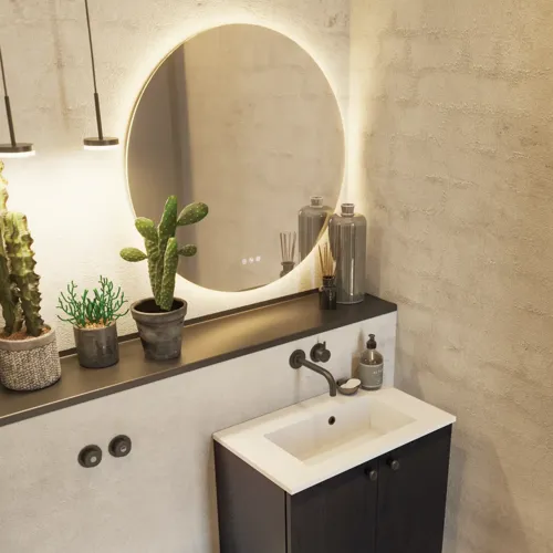 Badezimmerinspiration mit Waschtischunterschrank aus schwarzer Eiche sowie elegantem rundem Spiegel und Waschbecken, stilvollen Accessoires sowie Kaktuspflanzen und Wänden aus rohen Materialien verleihen einen rauen, industriellen und urbanen Look.