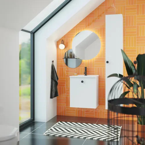 Badezimmer mit schräger Decke, inspiriert durch einen kleinen weißen Waschtisch und einen Hochschrank mit runden schwarzen Griffen, sowie einem schönen runden Spiegel, orangefarbene Fliesen geben einen frischen und modernen Look.