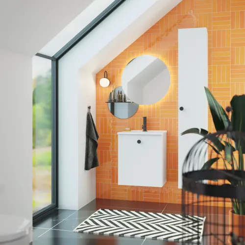 Badezimmer mit schräger Decke, inspiriert durch einen kleinen weißen Waschtisch und einen Hochschrank mit runden schwarzen Griffen, sowie einem schönen runden Spiegel, orangefarbene Fliesen geben einen frischen und modernen Look.