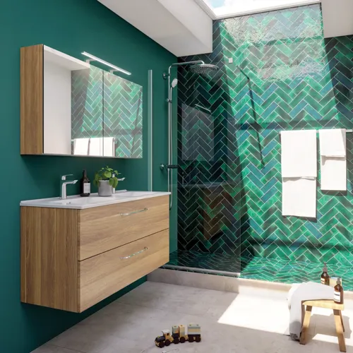 Großes Badezimmer mit einem Waschtisch in warmer Eiche, elegantem Doppelwaschbecken, schönem Spiegelschrank und Duschabtrennung, grünen Fischgrätfliesen für einen raffinierten Look.