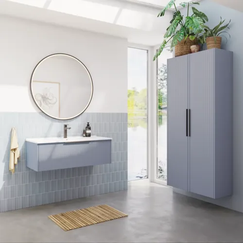 Badezimmerinspiration mit hellblauen Fliesen und Betonboden, elegantem hellblauem Waschtischunterschrank mit schmalen Streifen, dünnem Waschbecken, doppeltem Hochschrank und rundem Spiegel mit schwarzem Rand und Licht.