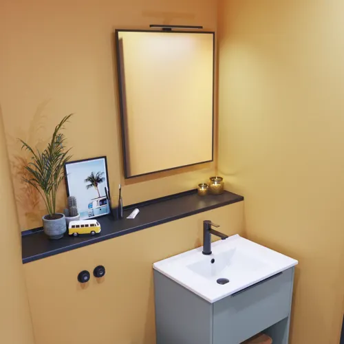 Kleine Badezimmerinspiration mit schrägen und warmen gelben Wänden, elegantem hellblauem Waschtisch, dünnem und stilvollem Waschbecken sowie minimalistischem quadratischem Spiegel mit schwarzem Rand und praktischer Lampe.