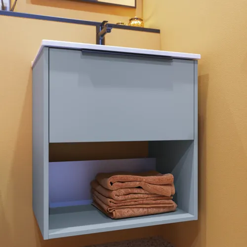 Kleine Badezimmerinspiration mit schrägen und warmen gelben Wänden, elegantem hellblauem Waschtisch mit offenem Fach, das eine einzigartige Atmosphäre schafft, dünnem und stilvollem Waschbecken, das Ihrem Badezimmer Praktikabilität und Eleganz verleiht.