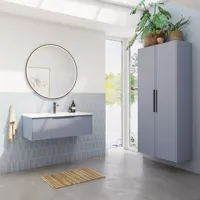 Badezimmerinspiration mit hellblauen Fliesen und Betonboden, elegantem hellblauem Waschtischunterschrank mit schmalen Streifen, dünnem Waschbecken, doppeltem Hochschrank und rundem Spiegel mit schwarzem Rand und Licht.