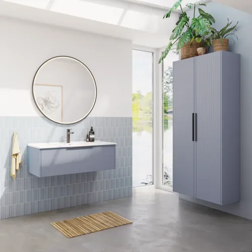Badezimmerinspiration mit hellblauen Fliesen und Betonboden, elegantem hellblauem Waschtischunterschrank mit schmalen Streifen, dünnem Waschbecken, doppeltem Hochschrank und rundem Spiegel mit schwarzem Rand und Licht.
